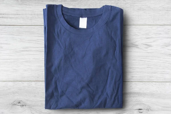 Folded blue basic t-shirt on white wooden background