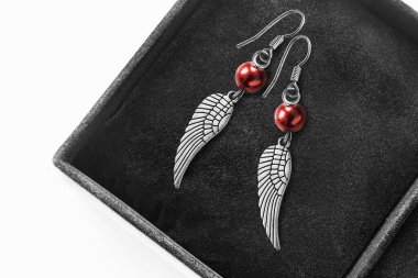 Siyah mücevher kutusunda gümüş kanatlar şeklinde damla küpeler.