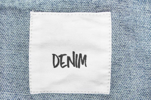 Clothes label says denim on blue jeans closeup