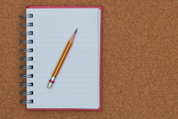 Open notebook and pencil on cork board background. — Stock Photo, Image