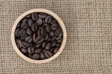 Üst manzara: Çuval desenli ahşap fincanda kahve çekirdekleri.