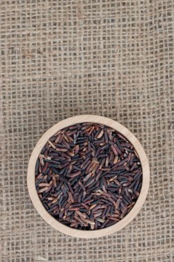 Üst manzara: Tahta kasede kahverengi pirinç (Rice Berry) çuval dokusunda.