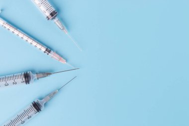 Mavi arka planda tıbbi şırıngaya yakın çekim. Kopyalama alanı olan üst görünüm.