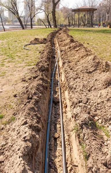 在靠近河流的树下的地下安装灌溉系统用的管子 乌克兰基辅Natalka公园的浇水系统 — 图库照片#