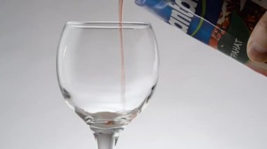 Pouring red wine into a glass close-up on a white background