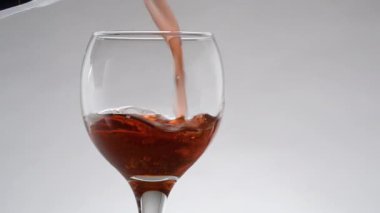 Pouring red pomegranate juice in glass close-up on white background