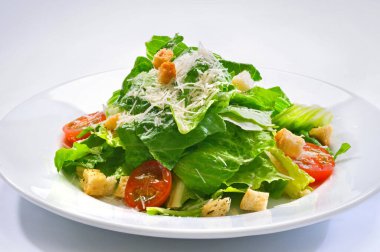 Çeri domatesli, kıtır kıtır salatalı ve rendelenmiş peynirli cam tabakta salata.