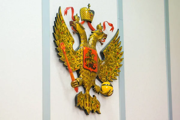 白い壁に黄金のロシアの紋章 ストック画像