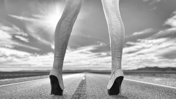 Female legs leather boots background of road and sky — Stock Photo, Image