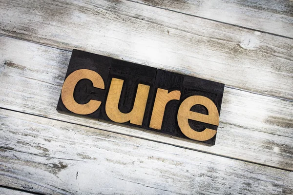 Cure Letterpress Word на деревянном фоне — стоковое фото