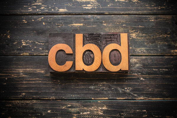 The word "CBD" written in vintage wood letterpress type on a vintage rustic background.