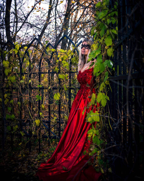 Mysterious woman in mask standing near fence. Autumn, fall