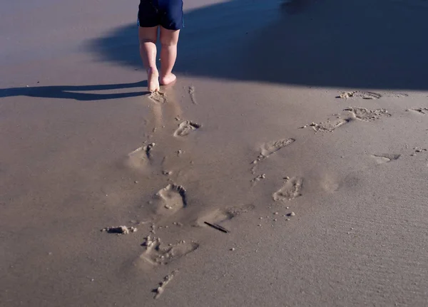 Mały Chłopiec Biegnie Wzdłuż Plaży Zostawia Ślady Stóp Piasku — Zdjęcie stockowe