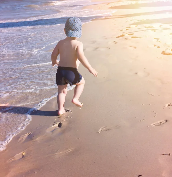 Mały Chłopiec Biegnie Wzdłuż Plaży Zostawia Ślady Stóp Piasku — Zdjęcie stockowe
