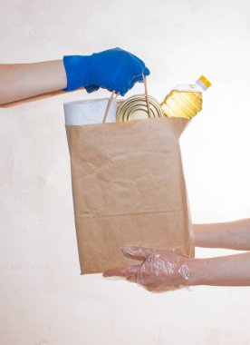  Elli teslimatçı tıbbi eldivenler karantina için yiyecek stokları içeren kağıt paketleri tutuyor. Pirinç, yağ, konserve yiyecek, tuvalet kağıdı. Yemek servisi. Bağış, koronavirüs. 