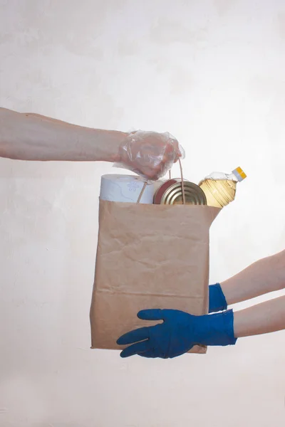  Elli teslimatçı tıbbi eldivenler karantina için yiyecek stokları içeren kağıt paketleri tutuyor. Pirinç, yağ, konserve yiyecek, tuvalet kağıdı. Yemek servisi. Bağış, koronavirüs. 
