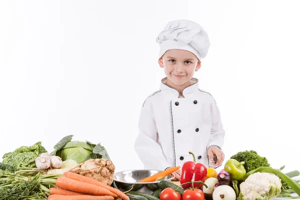 Een kleine jongen als chef kok maken salade, koken met groente — Stockfoto