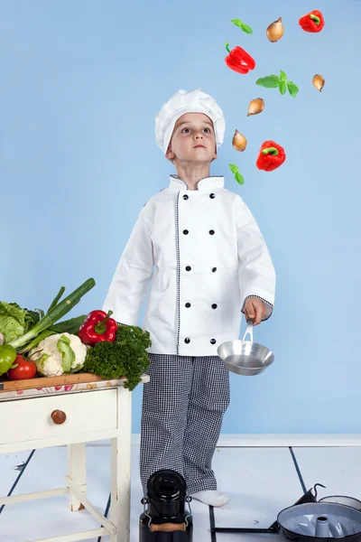 Een kleine jongen als chef kok maken salade, koken met groente — Stockfoto