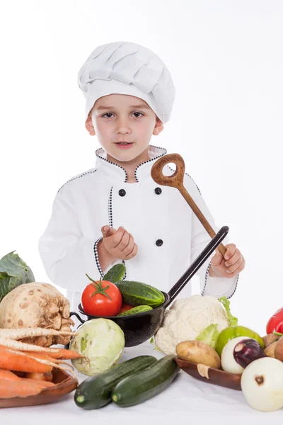 En liten gutt som kokk lager salat, lager mat med grønnsaker – stockfoto