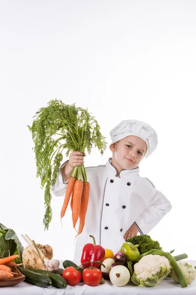 En liten gutt som kokk lager salat, lager mat med grønnsaker – stockfoto