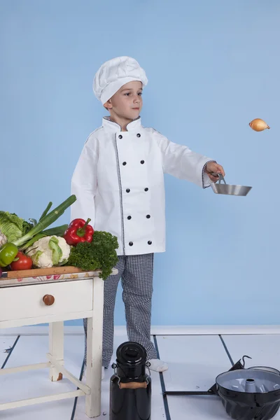 Een kleine jongen als chef kok maken salade, koken met groente — Stockfoto