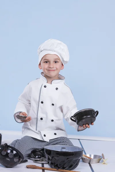 Een kleine jongen als chef kok maken salade, koken met groente — Stockfoto