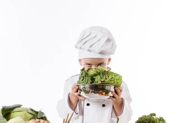 En liten gutt som kokk lager salat, lager mat med grønnsaker – stockfoto