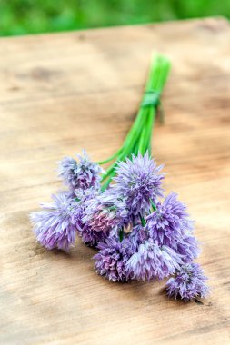 Çiçek chives bir snop bir doğal ahşap kesme tahtası üzerinde bağlı