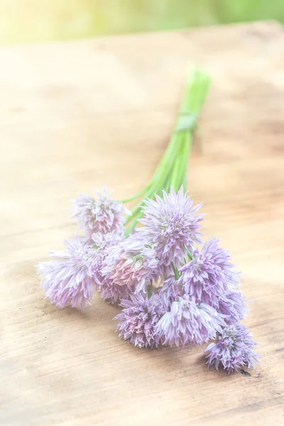 Ciboulette de fleurs attachée dans un snop sur une planche à découper en bois naturel — Photo