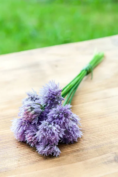 Ciboulette de fleurs attachée dans un snop sur une planche à découper en bois naturel — Photo