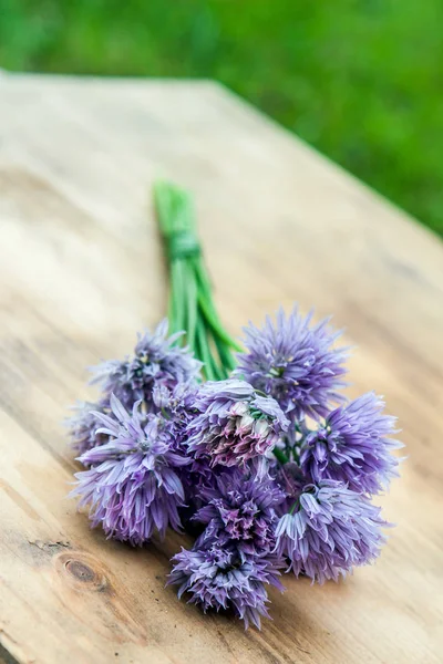 Ciboulette de fleurs attachée dans un snop sur une planche à découper en bois naturel — Photo