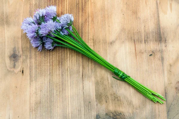 Ciboulette de fleurs attachée dans un snop sur une planche à découper en bois naturel — Photo