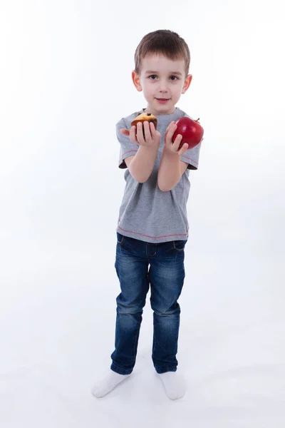 Niño pequeño con comida aislada sobre fondo blanco - manzana o magdalena — Foto de Stock