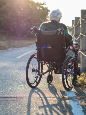 Yaşlı Asyalı kadınlar, yaşlılar, dışarıda tekerlekli sandalyeye otururlar.