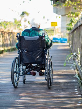 Yaşlı Asyalı kadınlar, yaşlılar, dışarıda tekerlekli sandalyeye otururlar.