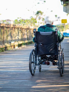 Yaşlı Asyalı kadınlar, yaşlılar, dışarıda tekerlekli sandalyeye otururlar.