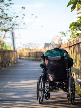 Yaşlı Asyalı kadınlar, yaşlılar, dışarıda tekerlekli sandalyeye otururlar.