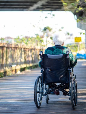 Yaşlı Asyalı kadınlar, yaşlılar, dışarıda tekerlekli sandalyeye otururlar.