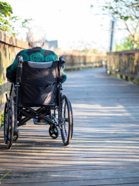 Yaşlı Asyalı kadınlar, yaşlılar, dışarıda tekerlekli sandalyeye otururlar.