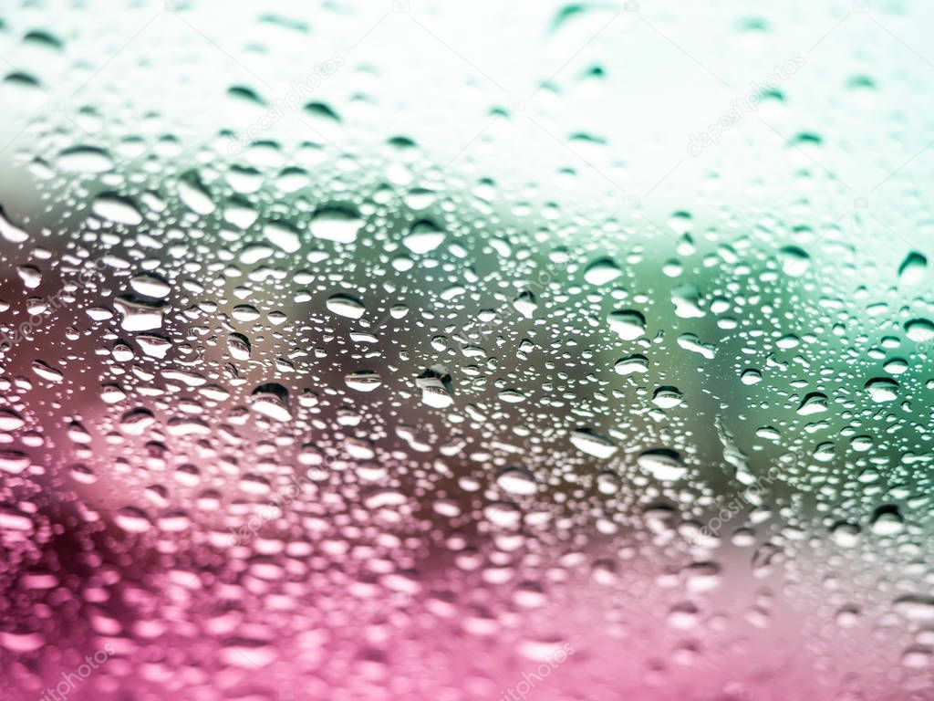 Close up view of colorful water drops falling on glass