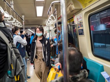 Taipei, Tayvan 'da toplu taşıma sisteminde yüz maskesi takan yolcular.