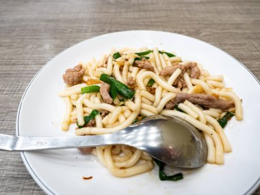 Kızarmış erişte, domuz eti ve yeşil soğanlı.