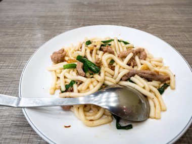 Kızarmış erişte, domuz eti ve yeşil soğanlı.