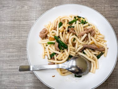 Kızarmış erişte, domuz eti ve yeşil soğanlı.