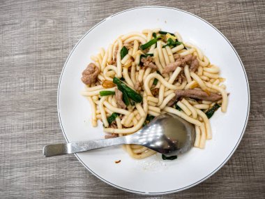 Kızarmış erişte, domuz eti ve yeşil soğanlı.