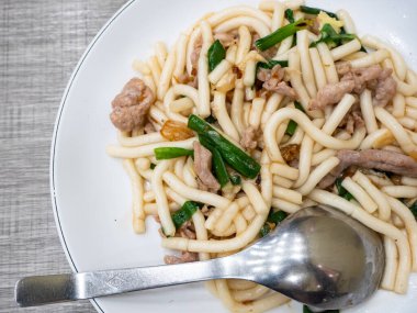 Kızarmış erişte, domuz eti ve yeşil soğanlı.