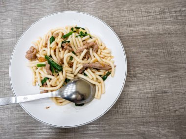 Kızarmış erişte, domuz eti ve yeşil soğanlı.