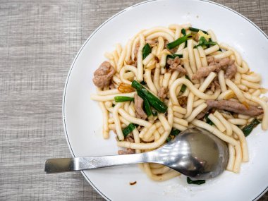 Kızarmış erişte, domuz eti ve yeşil soğanlı.