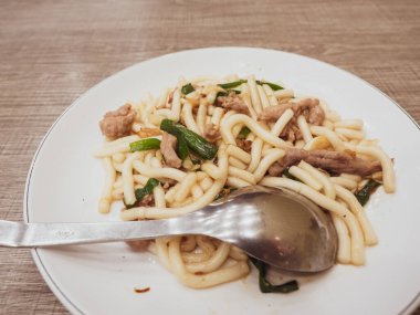 Domuz eti ve yeşil soğanlı kızarmış erişte.