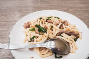 Domuz eti ve yeşil soğanlı kızarmış erişte.